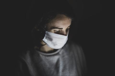 The Gospel message is that we are all one and need each other like the parts of a human body. (Unsplash/Engin Akyurt) Person in mask in mostly dark