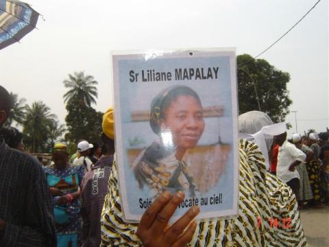 A funeral guest holds a flier depicting Sr. Liliane Mapalayi.