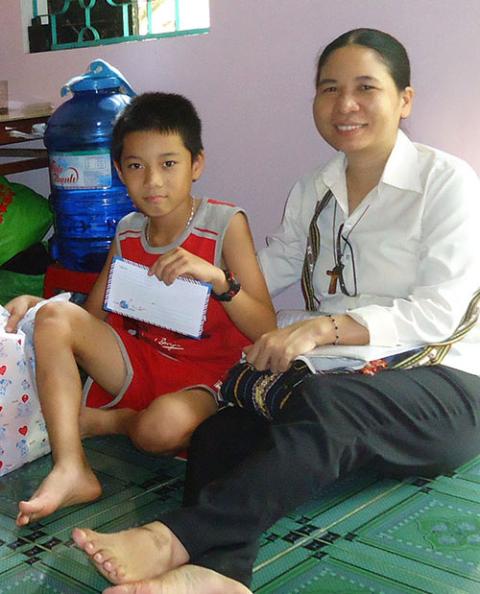 St. Paul de Chartres Sr. Elizabeth Tran Thi Hang hands a scholarship to a sixth-grader in Hue, Vietnam, on Oct. 9. (Peter Nguyen)