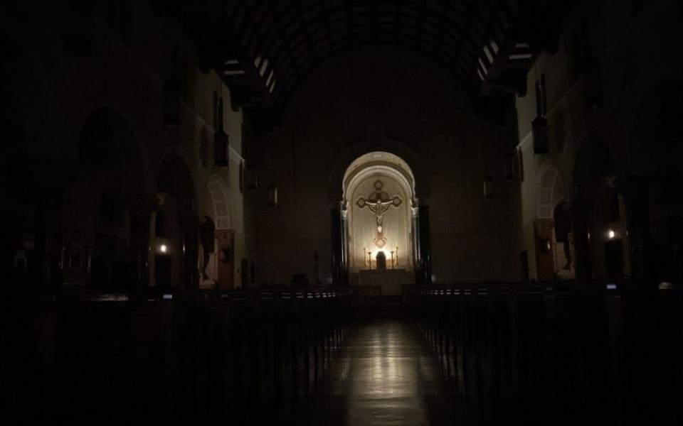 a dark empty church w/ light on the sanctuary