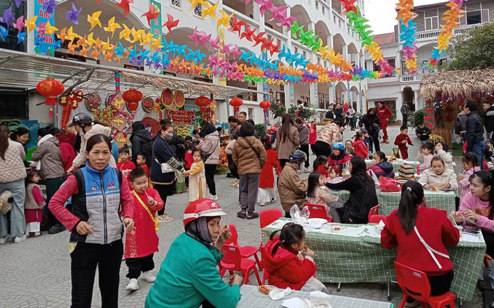 Parents and their children enjoy traditional food, buy vegetables, play folk games and watch a cultural performance by Lovers of the Holy Cross of Hung Hoa nuns on Jan. 29 at a day care center in Yen Bai City, Vietnam. (Joachim Pham)