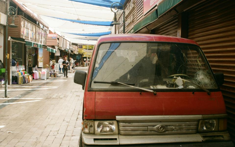 A red van with a cracked windshield parked on the side of the street.