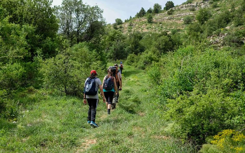 A group of people hiking a trail up a hill (Unsplash/Art of Hoping)