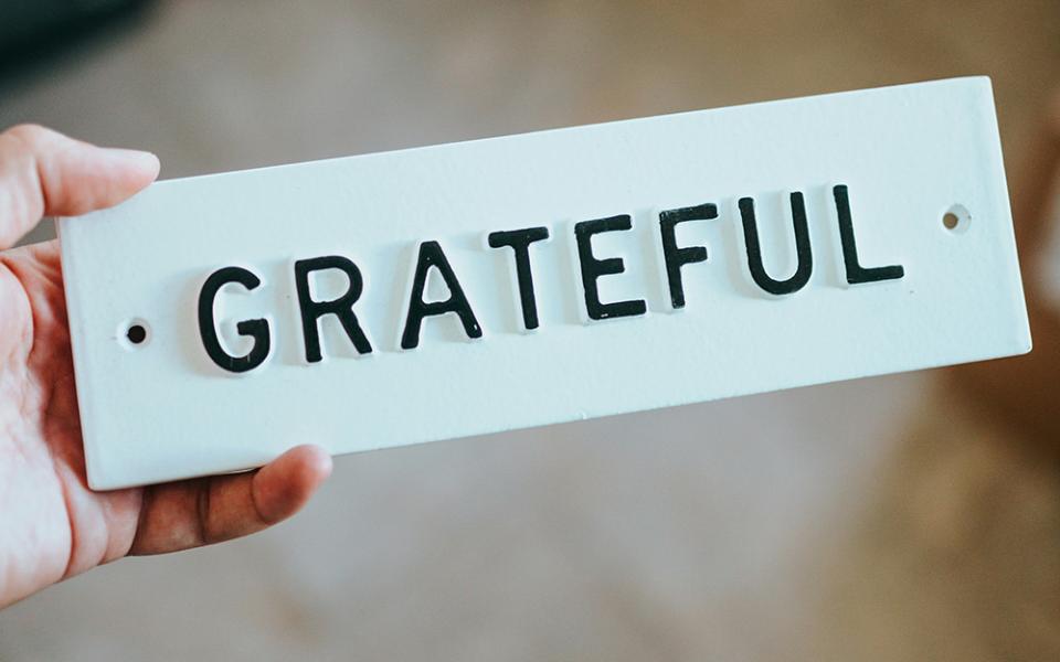 A white metal plate with the word GRATEFUL in raised black letters (Unsplash/Nathan Dumlao)