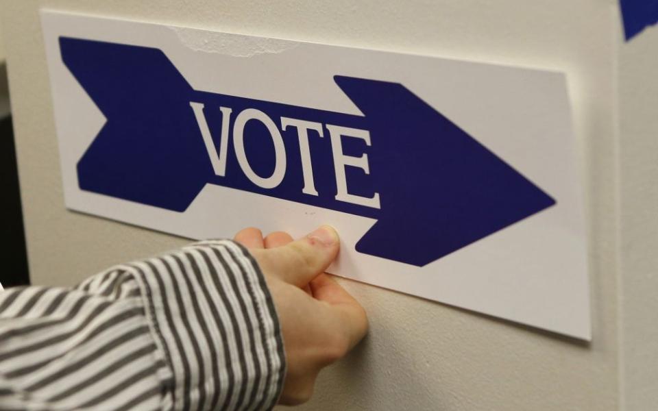An election worker puts up a sign at a polling station in McLean, Va. (OSV News/Reuters/Kevin Lamarque)