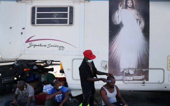 Haitian migrants trying to reach the United States watch another Haitian get a haircut outside a shelter after arriving in Monterrey, Mexico, on Sept. 24. (CNS/Reuters/Edgard Garrido)
