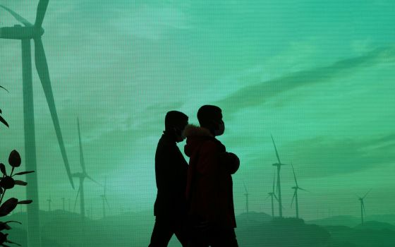 Delegates walk past a screen Nov. 1 during the U.N. Climate Change Conference, COP26, in Glasgow, Scotland. (CNS/Reuters/Yves Herman)