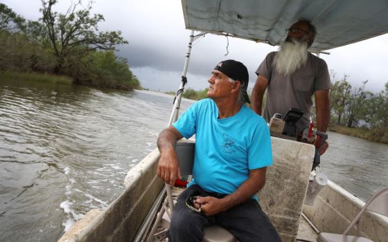 Donald Dardar, left, and Russell Dardar look toward the eroding shoreline of Bayou Pointe-au-Chien in southern Louisiana in September. The brothers have lived along the bayou all their lives as shrimpers and fishermen.(AP/Jessie Wardarski) 