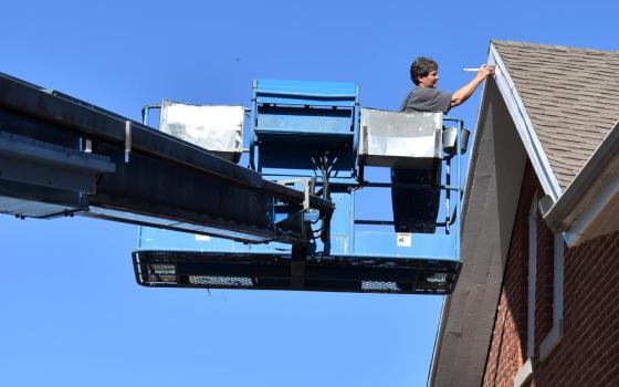 Benedictine Oblate Sr. Elaine Fischer is maintenance director at Mount St. Scholastica in Atchison, Kansas. She isn’t afraid of heights: Here she uses the lift reach the eaves of the maintenance shed for painting. (Julie A. Ferraro)