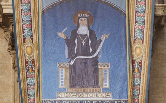 A tapestry showing 12th-century German abbess St. Hildegard of Bingen hangs from the facade of St. Peter's Basilica prior to the opening Mass of the Synod of Bishops for the new evangelization in St. Peter's Square Oct. 7, 2012, at the Vatican. (CNS)