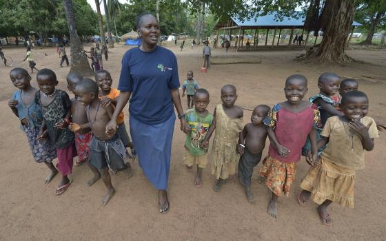 Sr. Josephine Murigi, a member of Our Lady of the Missions and Solidarity with South Sudan, walks with children in a camp for more than 5,000 displaced people in Riimenze in June 2017. Families were displaced in late 2016 and early 2017 as fighting betwee