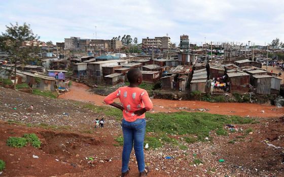 A young woman stands on a hillside looking over a poor section of Nairobi, Kenya, April 19, 2020, during the COVID-19 pandemic. (CNS/Reuters/Thomas Mukoya)