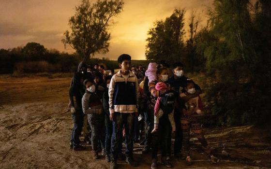 Migrants from Central America seeking asylum in the United States line up May 15 to be escorted to the main road by the Texas Army National Guard in Roma, Texas, after crossing the Rio Grande. (CNS/Reuters/Adrees Latif)