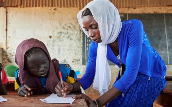 woman helps student at a desk