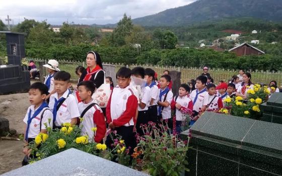 A nun takes children to the holy land, or cemetery, at Thai Xuan Parish in Xuan Loc Diocese to pray for the souls after Mass. (Photo courtesy of Mary Nguyen Lan)