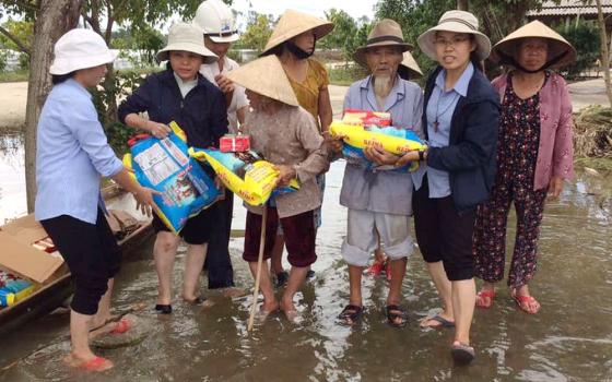 Nguyen Chac (third from right) receives food from Lovers of the Holy Cross of Hue, Vietnam, Oct. 3. (GSR photo/Joachim Pham)