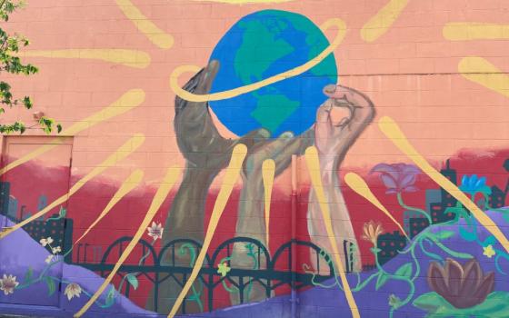 street art shows arms and hands of different colors holding up the earth