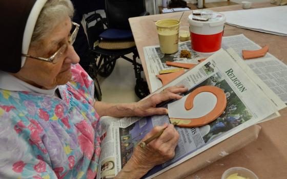 Sylvania Franciscan Sr. Jane Mary Sorosiak paints colored glaze onto a ceramic tile. When the painting is complete, the tile will be baked to harden the glaze into a permanent coating. (GSR photo/Dan Stockman)