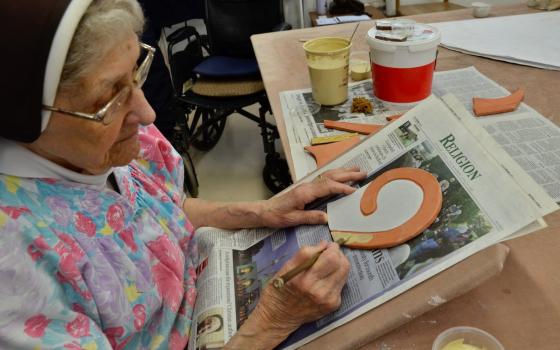 Sylvania Franciscan Sr. Jane Mary Sorosiak paints colored glaze onto a ceramic tile. When the painting is complete, the tile will be baked to harden the glaze into a permanent coating. (GSR photo/Dan Stockman)