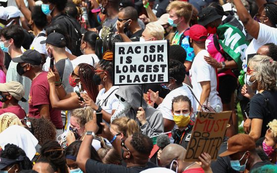 Protesters in Washington stand with a sign reading "Racism is Our Longest Plague" Aug. 28, 2020, at the spot where civil rights leader the Rev. Martin Luther King Jr. delivered his "I Have a Dream" speech. (CNS/Reuters/Tom Brenner)