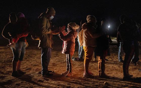 Romando, a migrant from Peru seeking asylum in the United States, plays a hand-clapping game with his daughter Alexa, 7, as they stand in line waiting to be processed in Roma, Texas, Feb. 28. (CNS/Reuters/Adrees Latif)