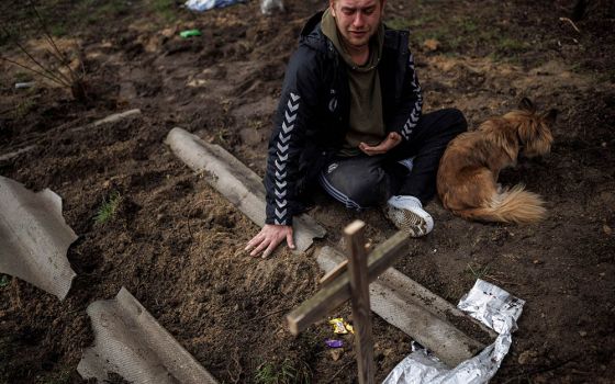 Serhii Lahovskyi, 26, mourns next to the grave of his friend Ihor Lytvynenko after Lytvynenko was found beside a building's basement in Bucha, Uraine, April 6. Residents say Russian soldiers killed Lytvynenko. (CNS/Reuters/Alkis Konstantinidis)