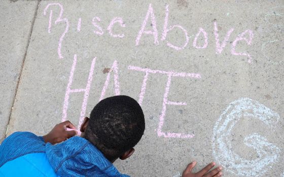 A boy writes a message on a sidewalk May 18 in Buffalo, New York, where a mass shooting took place May 14 at a Tops supermarket. (CNS/Reuters/Brendan McDermid)