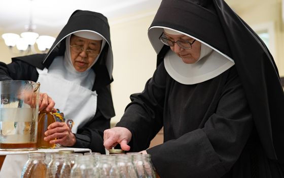 Sr. Margaret Muraki, left, and Mother Emily Ann Lindsey, both All Saints Sister of the Poor, screw caps onto jars of honey produced by bees on the sister's property in Catonsville, Maryland, on Aug. 16. (CNS/Catholic Review/Kevin J. Parks)