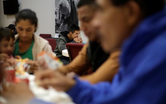 Migrants from Central America sit at tables, eating