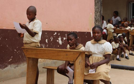 Three Cameroonian children sit at a desk