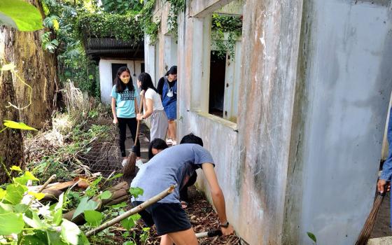 Under the leadership of the Sisters of the Good Samaritan, students collect trash at what remains of the small building of the homeowners' association, in the park they are rehabilitating in the city of Bacolod, in Negros Occidental, the Philippines. (Courtesy of the Sisters of the Good Samaritan)