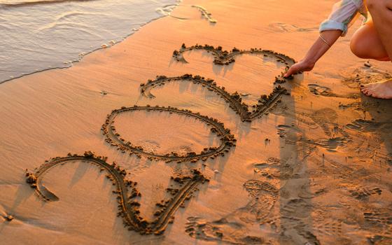 A girl writes 2023 in the sand on a beach (Unsplash/Engin Akyurt)