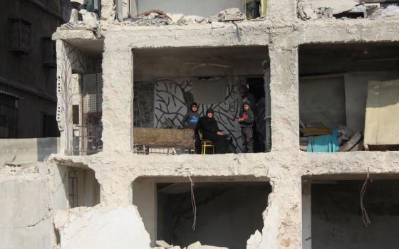 A Syrian earthquake survivor sits with her grandchildren inside the shell of her son's destroyed home in Aleppo Feb.13. (