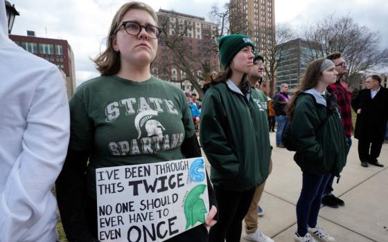 : Katie Denzin, who attended Saugus High School in California, holds a sign with current and former Michigan State University students during a Feb. 15 rally at the capitol in Lansing, Michigan. A gunman killed three students and critically injured five others Feb. 13 on Michigan State University's campus.