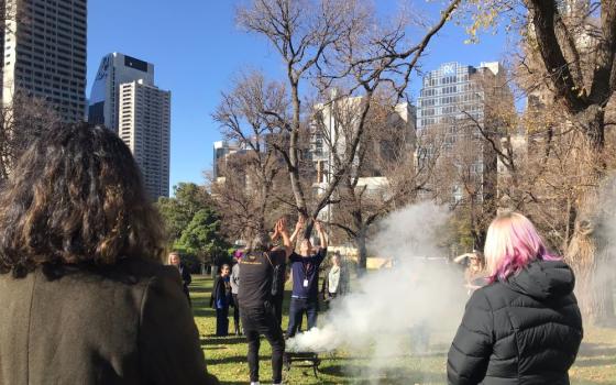 Women watch a healing ceremony that includes smoke.