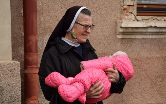 Nun holds baby.