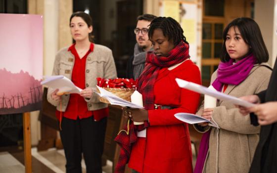 Four young people, two wearing red, hold sheets of paper