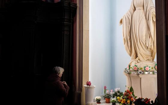 A woman prays in front of a statue of Mary on March 29, 2022, inside Bernardine Monastery in Lviv, Ukraine. (CNS/Reuters/Alkis Konstantinidis)