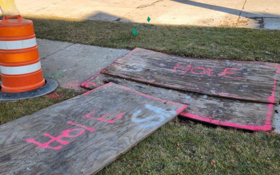 Pieces of wood marked "hole" cover spots where workers are repairing utility lines.