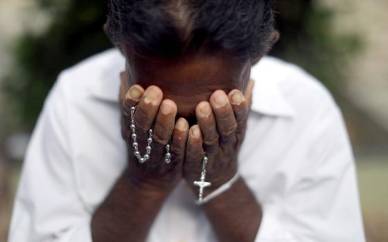 A person mourns near the grave of a suicide bombing victim at Sellakanda Catholic cemetery April 23, 2019, in Negombo, Sri Lanka. (CNS/Reuters/Athit Perawongmetha)