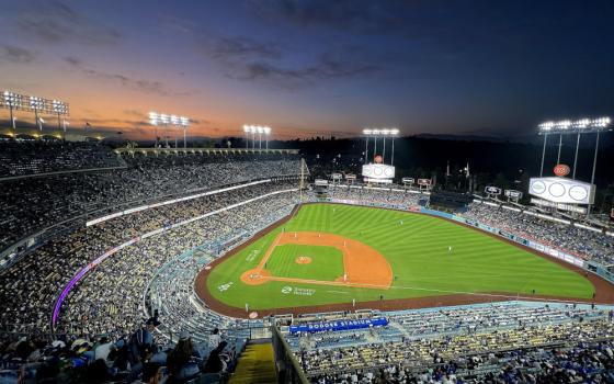 A baseball stadium is lit up at night as the sun slips below the horizon