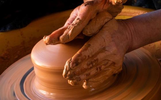 hands molding clay on a potters wheel