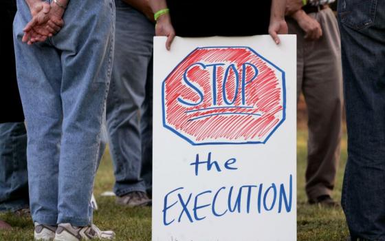 Hands are shown holding a sign that reads, "Stop the Execution."