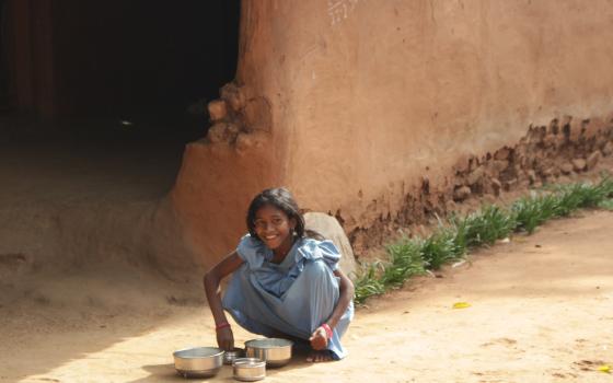 Little girl smiles as she squats at the side of the street