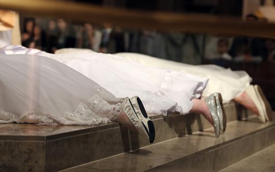 Three women consecrated as virgins lie prostrate during a 2017 ceremony. Pope Francis praised consecrated virgins June 1, 2020, the 50th anniversary of St. Paul VI's revival of the "Ritual for the Consecration of Virgins." (CNS/Joel Breidenbach)