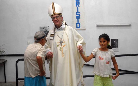 Argentine Cardinal Jorge Mario Bergoglio, elected March 13, 2013 as Pope Francis, holds the hands of a woman and girl during Holy Thursday Mass in 2008 at a church in a poor section of Buenos Aires, Argentina. (CNS/Reuters/Enrique Garcia Medina)