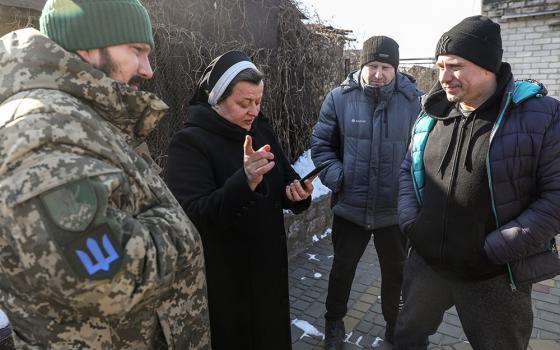 Basilian Sr. Lucia Murashko talks with volunteers Denys Kuprikov, left, and Ivan Smyglia, far right, in Zaporizhzhia in southeast Ukraine Feb. 7 about where they will distribute humanitarian aid along the front in Russia's war against Ukraine. (OSV News/CNEWA/Konstantin Chernichkin)