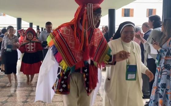 A dancer from the Fe y Alegria School escorts Sr. Silvia Flores, right, to the opening of the board meeting of the Confederation of Latin American and Caribbean Religious June 2, in Lima, Peru.