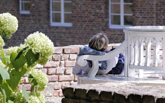 A person relaxes on a chair in a garden.