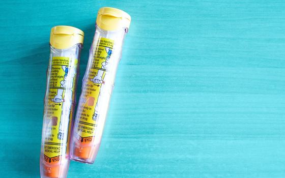 Two epipens on a blue wooden background (Unsplash/Pixielumina Photography)